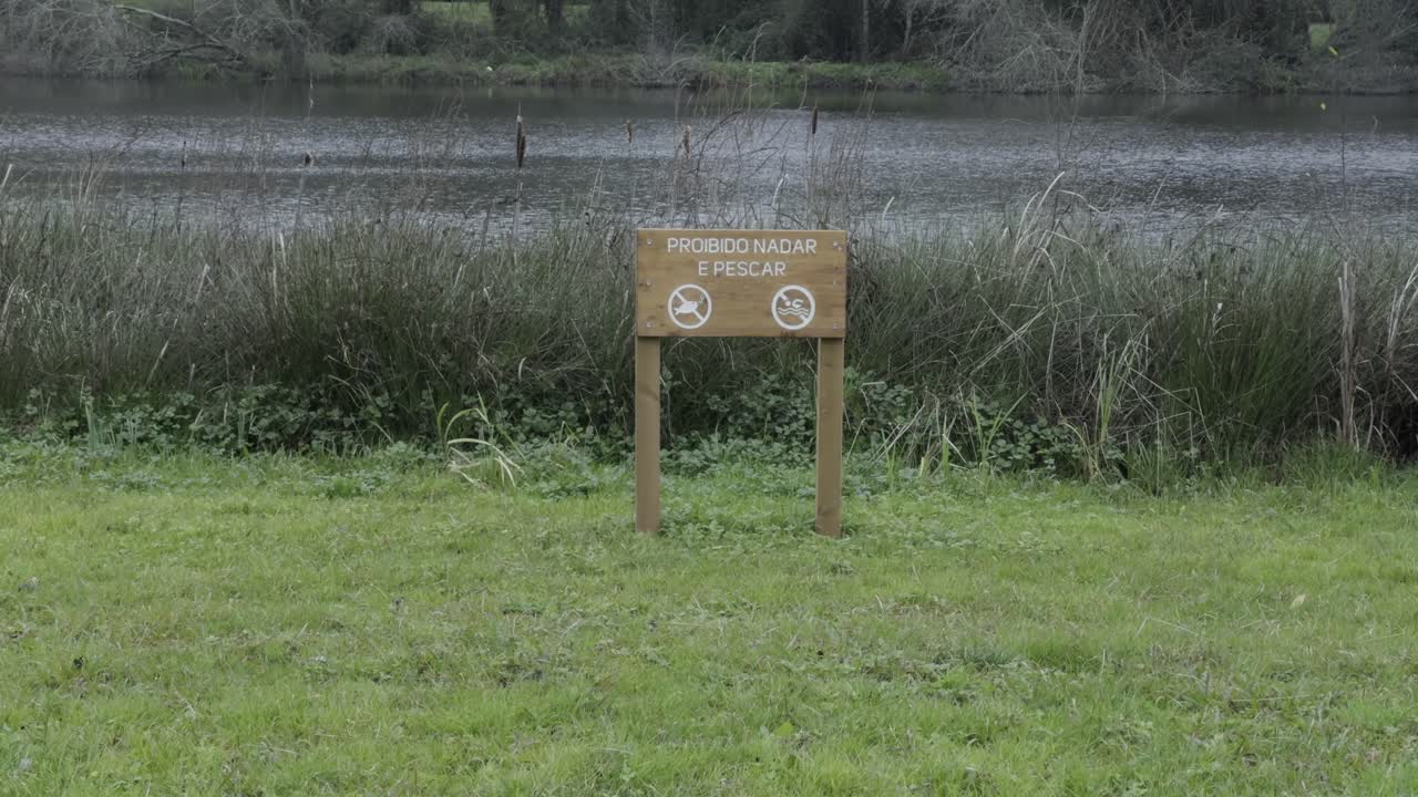 Cartello di avvertimento che proibisce la pesca vicino a un lago calmo circondato da erba e canne