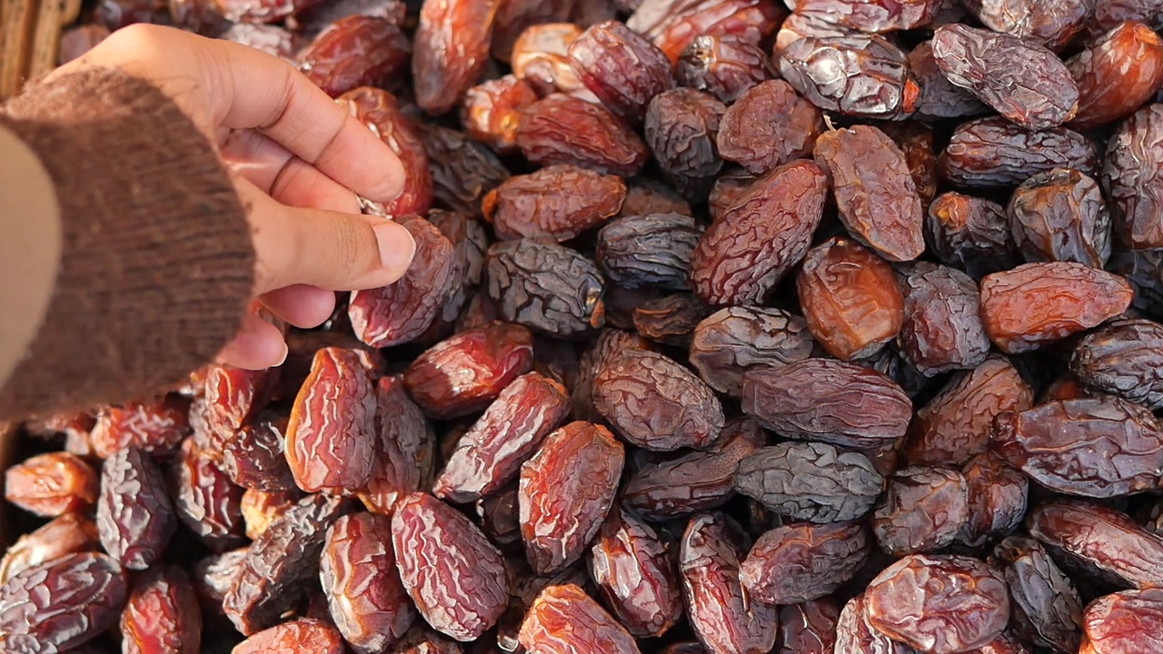 Hand Picking a Dried Date from a Pile