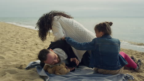 playful parents child enjoying family vacation on sea beach picnic outdoors.