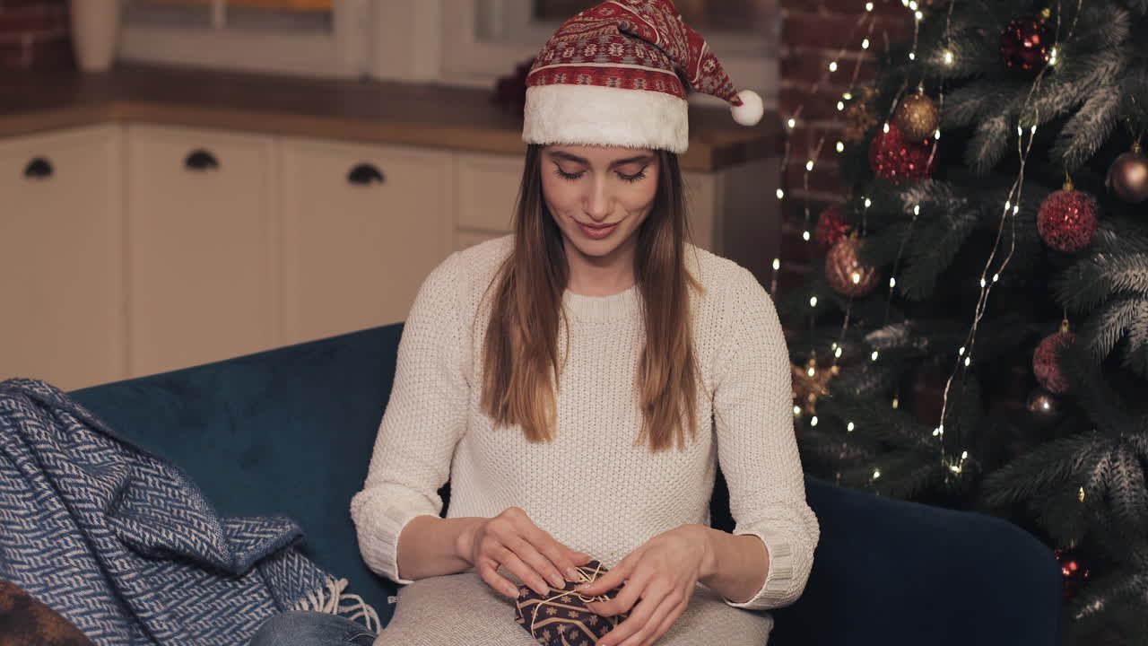 Woman in Santa hat sitting near Christmas tree
