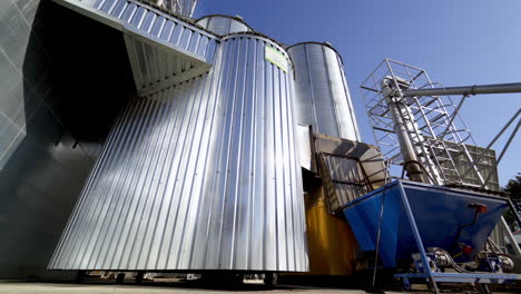 metal granary at sunlight. modern plant for processing agricultural harvest. silver grain elevators in summer. industrial complex for storing crop. close-up.