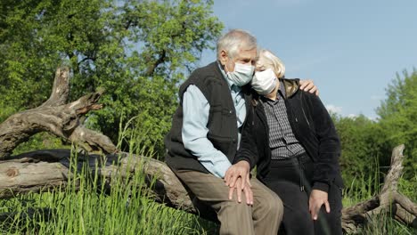 senior couple in medical masks during covid-19 coronavirus quarantine in park