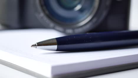 notepad, pen and camera on table