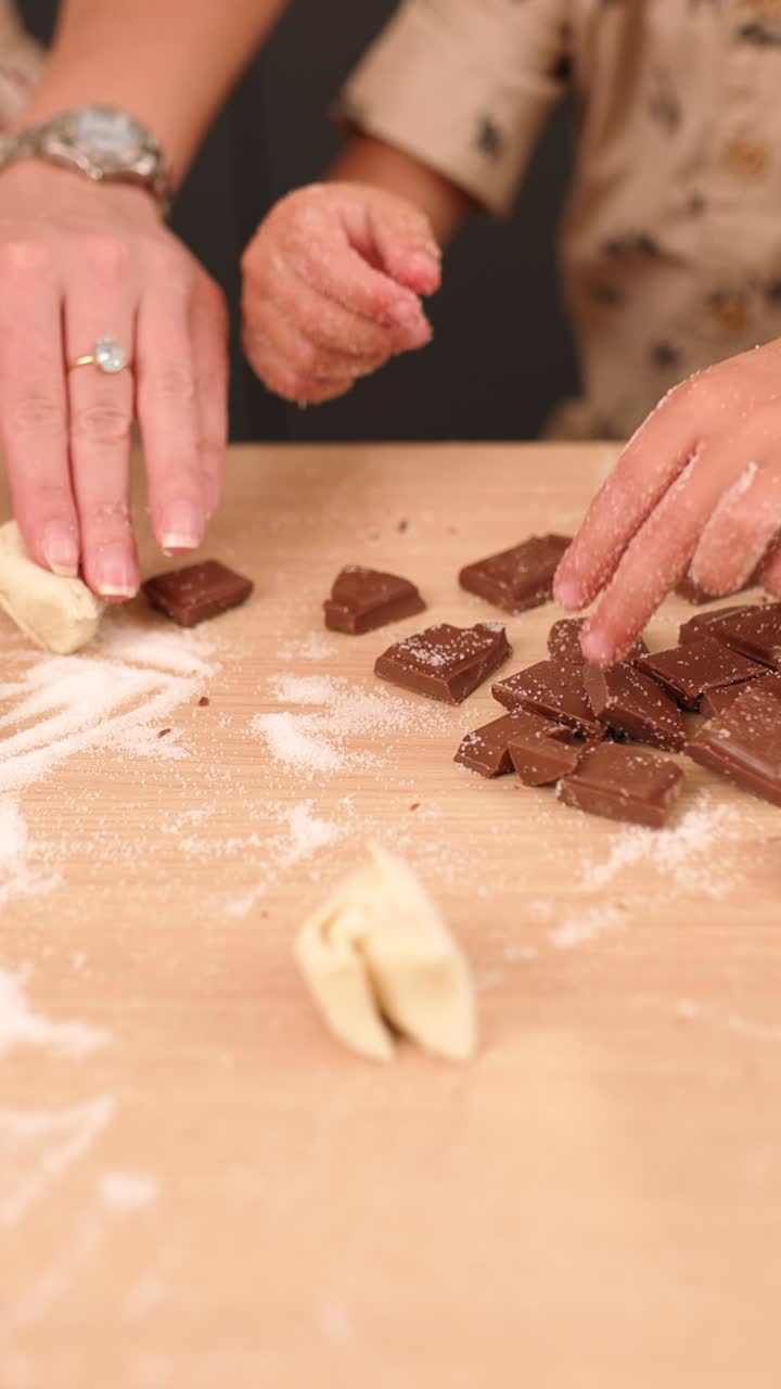 Mother and child preparing chocolate biscuits on kitchen table