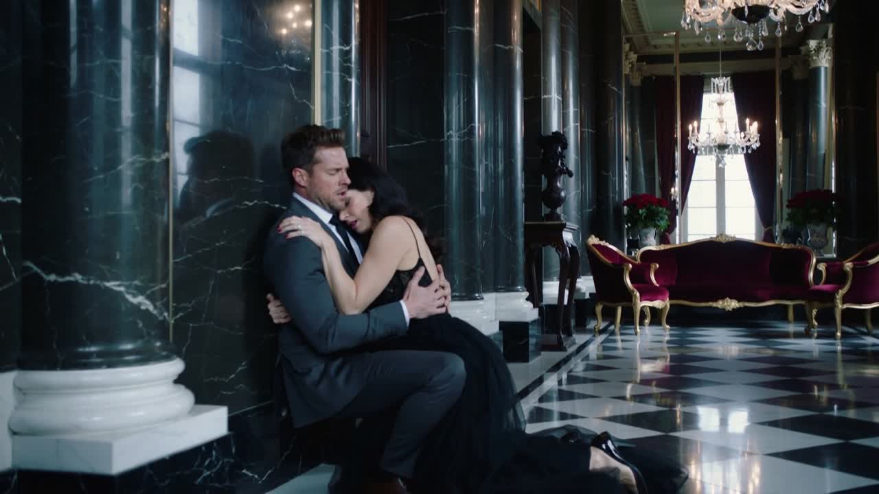 Black-gowned woman rushing into suited man's arms, sliding down hall column for help, copy space
