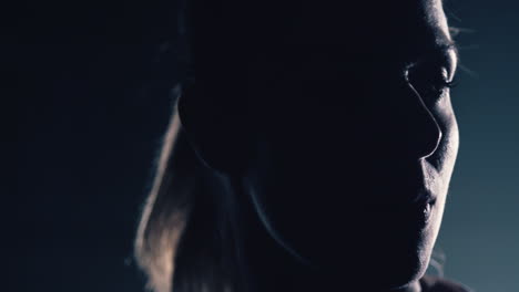 swedish young woman turns around and faces the spotlight alone in the dark. close up shot in slow motion.