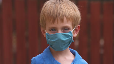 cute little boy in a face mask turns toward the camera