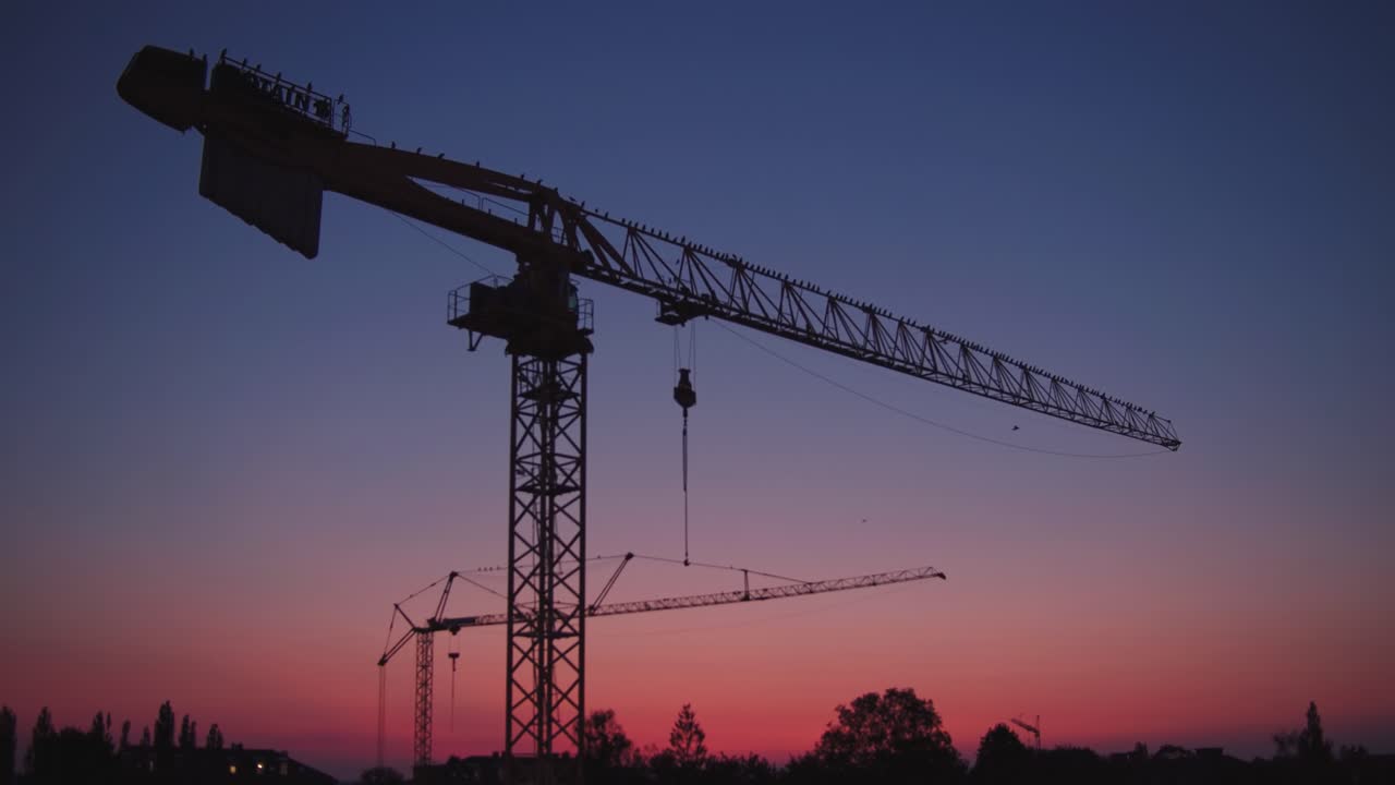 los cuervos se sientan en una grúa en el sitio de construcción al atardecer