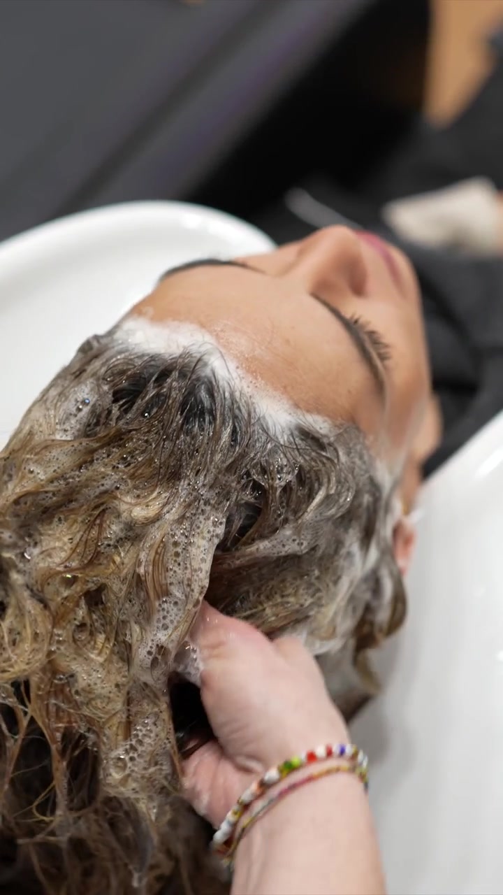 Parrucchiere che lava i capelli del cliente nel lavatesta del salone