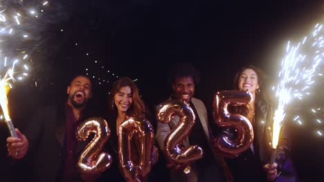 group of friends holding 2025 balloons and sparklers celebrating new years