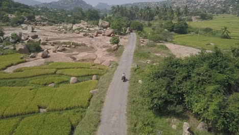 Luftaufnahme-Folgt-Motorrad-Durch-Naturwunder,-Hampi-Valley,-Indien