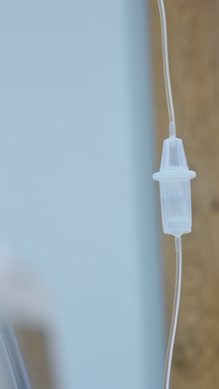 Female nurse looks at the drop counter with dripping medicines. Medical equipment working in the hospital ward. Vertical video