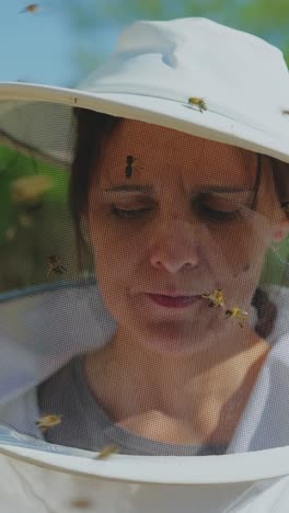 woman beekeeper wearing protective veil with bees