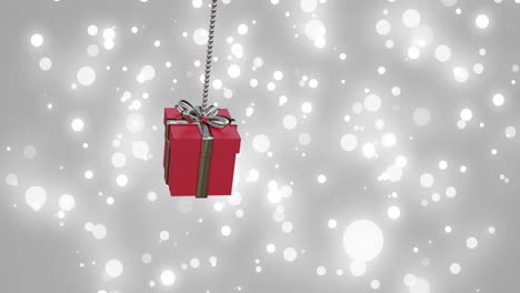 animation of red christmas gift bauble and snow falling on grey background