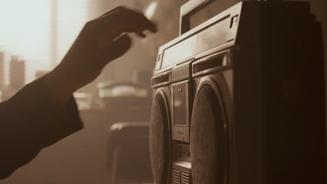 hand inserting audio cassette into retro boombox in softly lit room