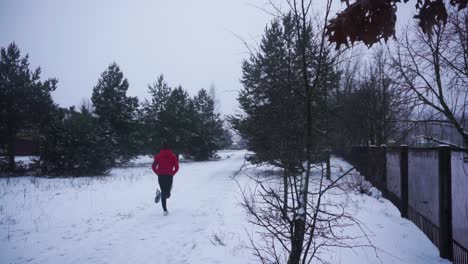 young man with red hoodie and black pants is running outside in winter