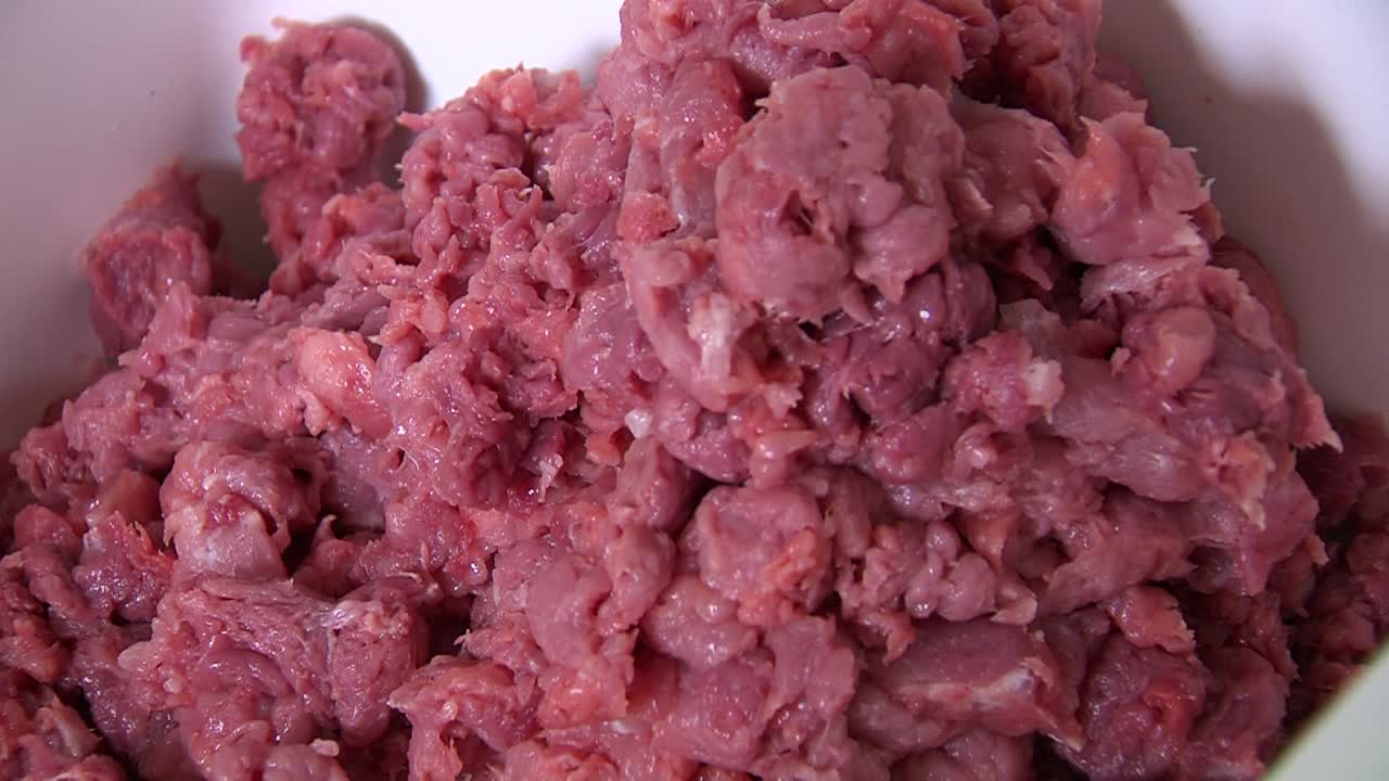 trozos de carne picada roja se amontonan en un recipiente blanco, cerrados en carnicería