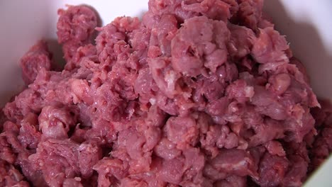 pieces of red minced meat pile up in white container, closeup in butchery