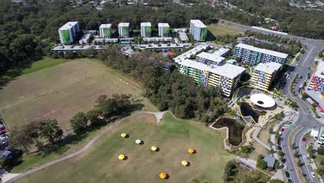 open green space of village heart with apartment buildings in the background in southport, queensland, australia. aerial drone shot