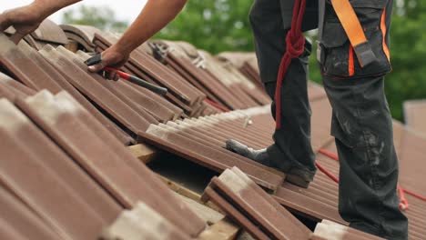 low angle static shot of a person putting back roof tiles after adding solar panel mounts in slow motion