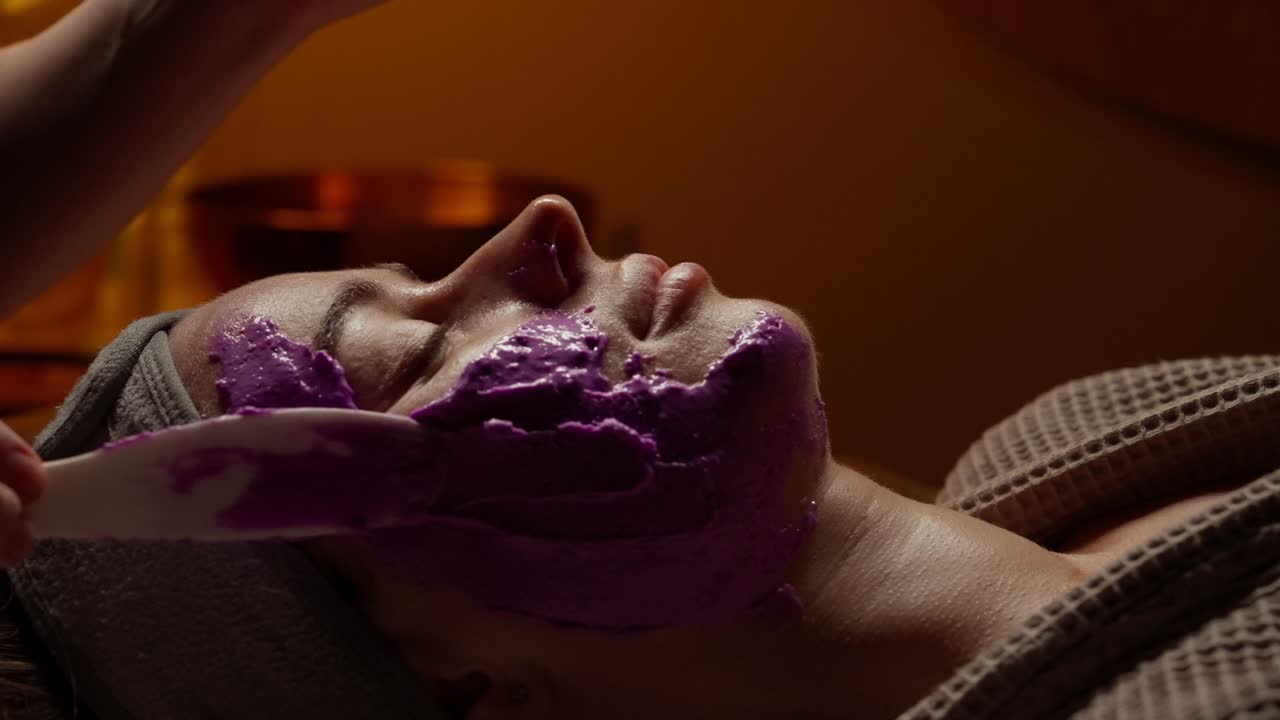 Kvinde modtager en lilla ansigtsmaskebehandling på et spa