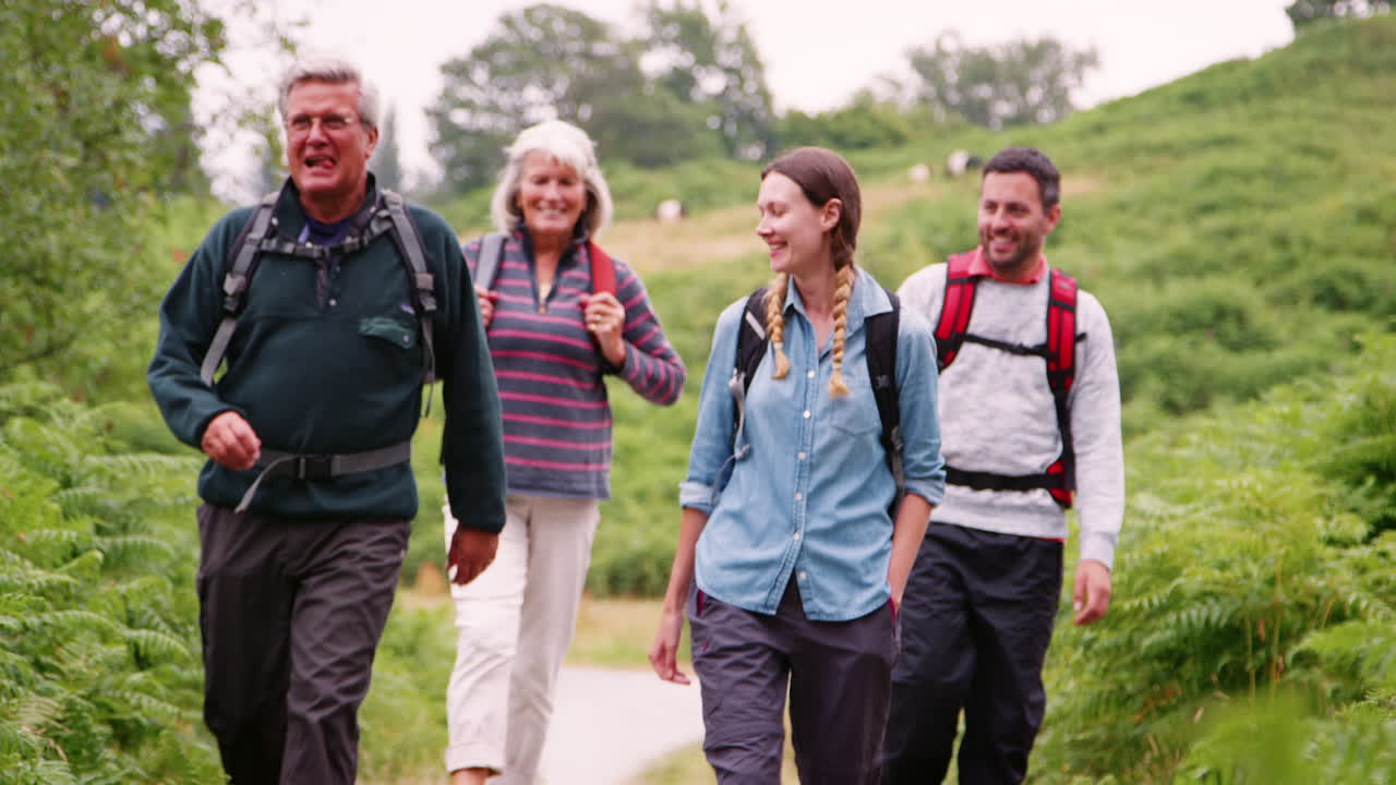 Two mixed age couples  walking on a countryside path during family camping adventure, Lake District, UK