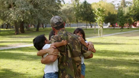 familia feliz dando la bienvenida al padre en el parque