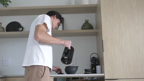 man pouring hot water on teapot from electric kettle