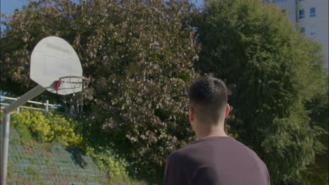 Tiro-Medio-Desde-Atrás-De-Un-Joven-Caucásico-Disparando-Un-Tiro-De-Tres-Puntos-En-Cámara-Lenta-En-Una-Cancha-De-Baloncesto-De-La-Ciudad-En-Un-Día-Soleado