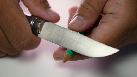 imágenes de manos afilando lentamente un lápiz y algunos lápices de colores con un cuchillo afilado