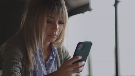 young asian girl using her smartphone looking around with a smile. modern devices gadgets addiction being online. social networks. chinese woman reading message on smartphone smile