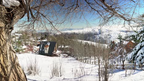 Looking-down-from-snowy-woodland-hillside-to-scenic-Farellones-village-neighbourhood-in-the-valley-of-the-Andes-mountains,-Santiago,-Chile