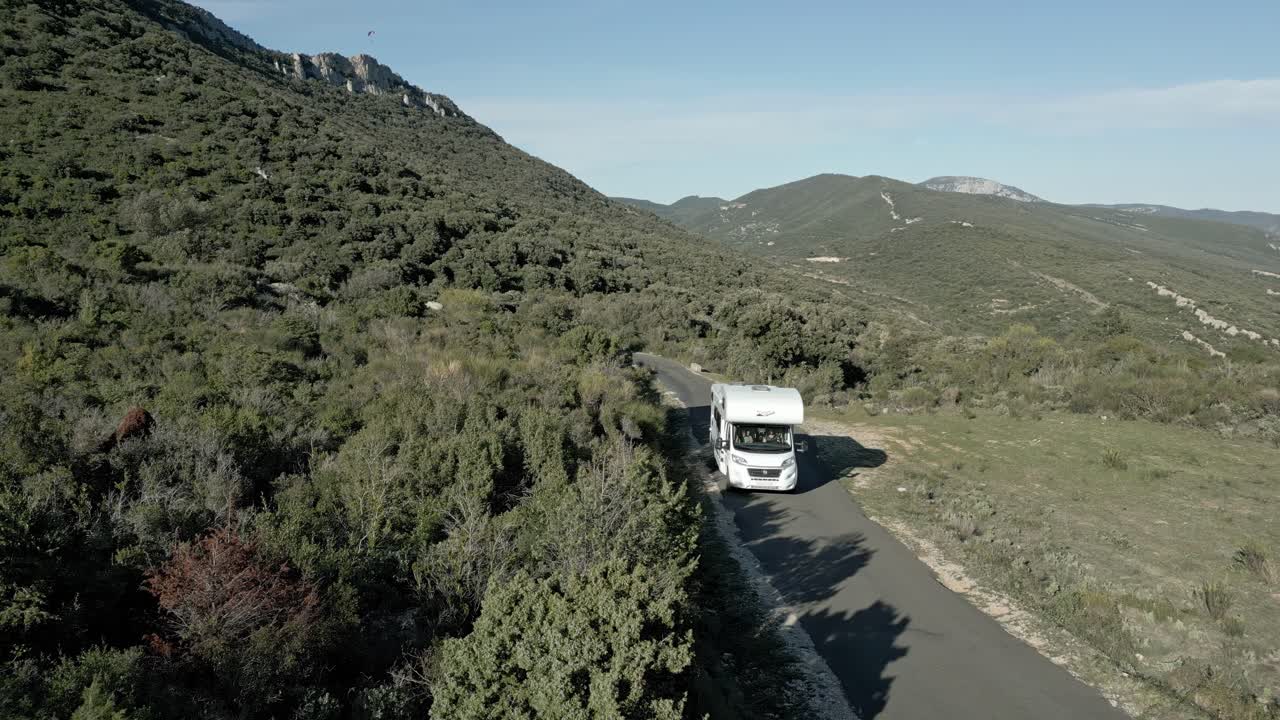Aerial Establishing Shot, White RV Camper Van Drives Through Green Hills Road, Pyrenees Mountains of South France, Camping Car