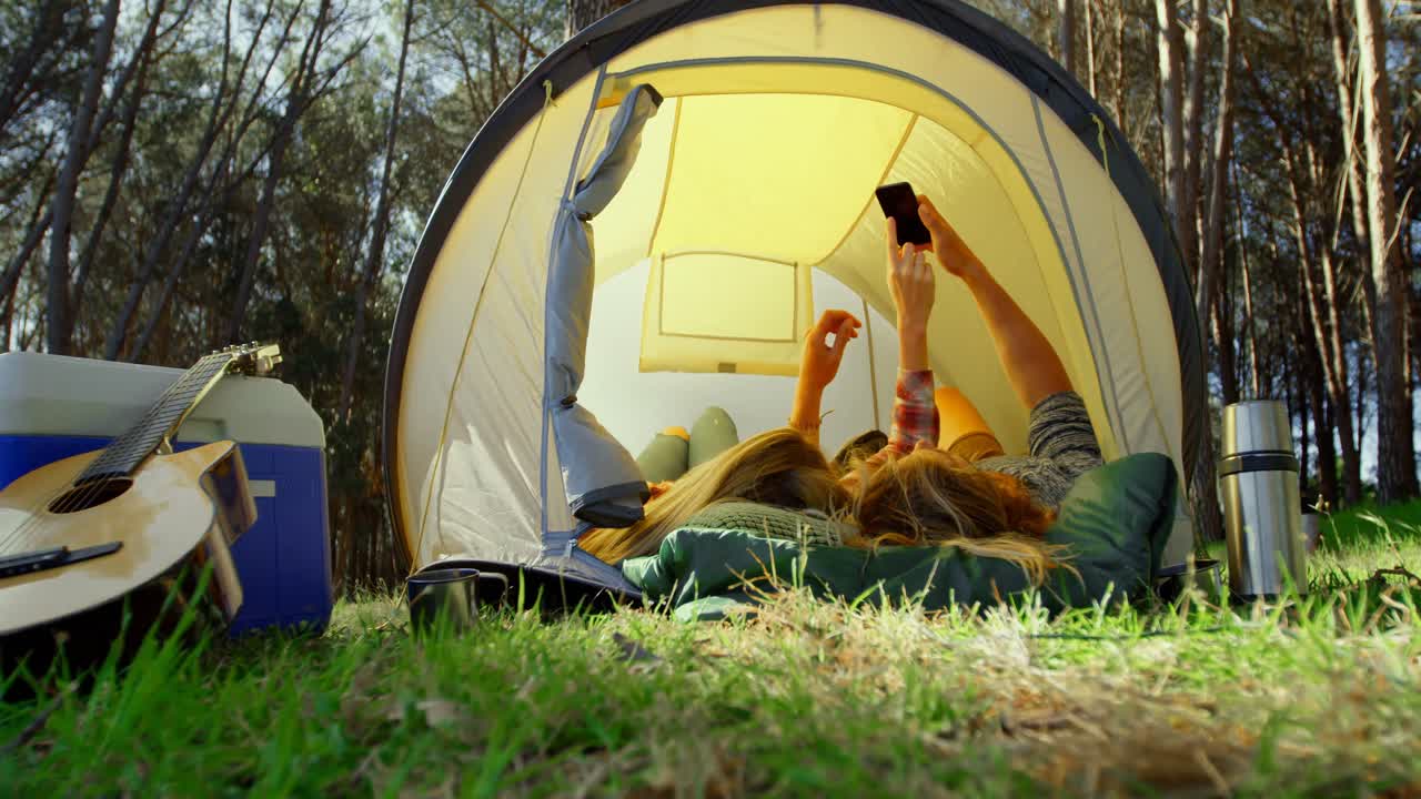 젊은 부부가 텐트 4k에서 휴대 전화로 셀카를 클릭합니다.