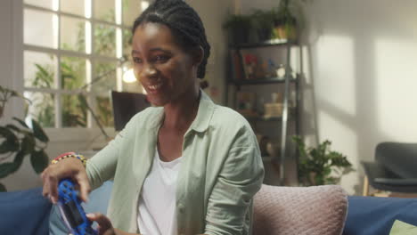 smiling black woman playing video games at home
