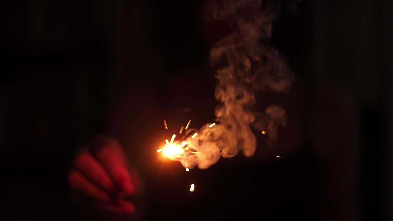 Hand Holding a Burning Sparkler in the Dark