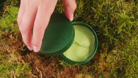 bottle of cosmetics cream serum on moss forest background green leaves. woman make up healthy natural products.