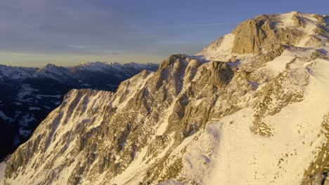 cinematic aerial shot of snowy peaks lighting in golden sunlight during sunset time - monte viezzena,italy