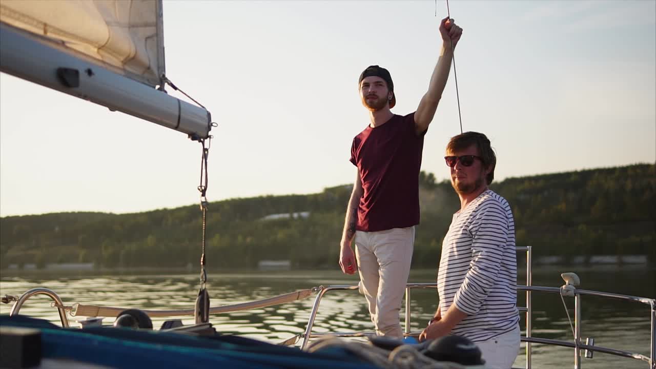 Two friends on a sailboat at sunset