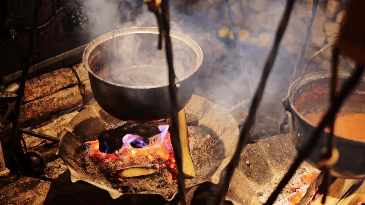 Slow motion captures boiling meal on flames as smoke drifts in cold evening air