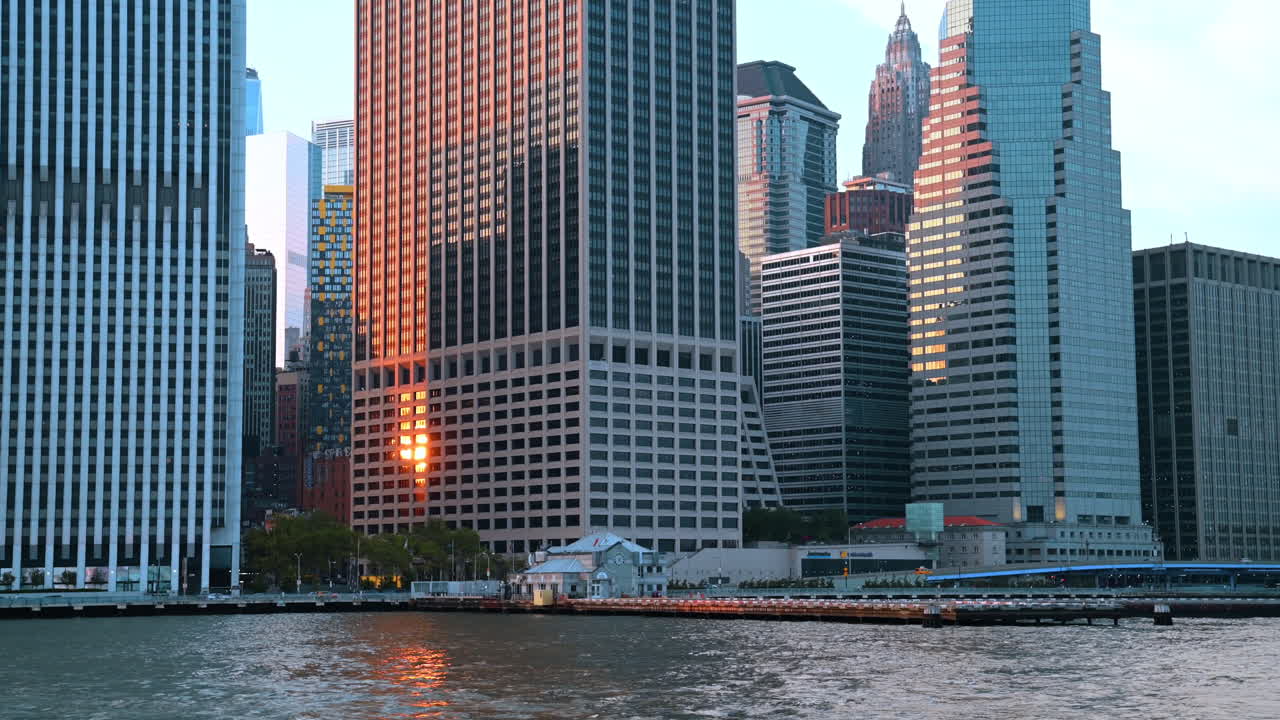 Nova Iorque, EUA, 9 de agosto de 2025: Agrupamento denso de arranha-céus no distrito financeiro ao pôr do sol. Vista do horizonte de Lower Manhattan refletindo a luz da hora dourada do outro lado da água.