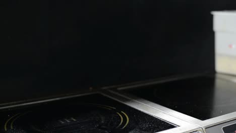 chef cooking steaming hot vegetables on induction hob in restaurant kitchen, closeup