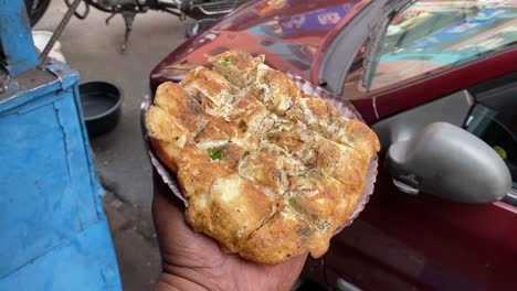 zoom out shot of bread omelette been served as breakfast from a roadside stall in india