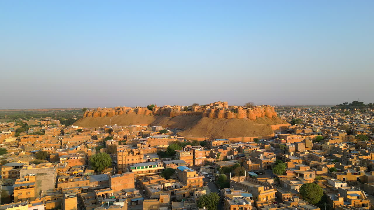 una impresionante toma de drone del fuerte de jaisalmer, rajasthan, brillando en piedra arenisca dorada bajo un cielo soleado el fuerte se eleva sobre un vibrante paisaje urbano de la india 4k