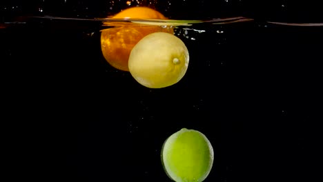 colorful citrus fruits being dropped into water in slow motion