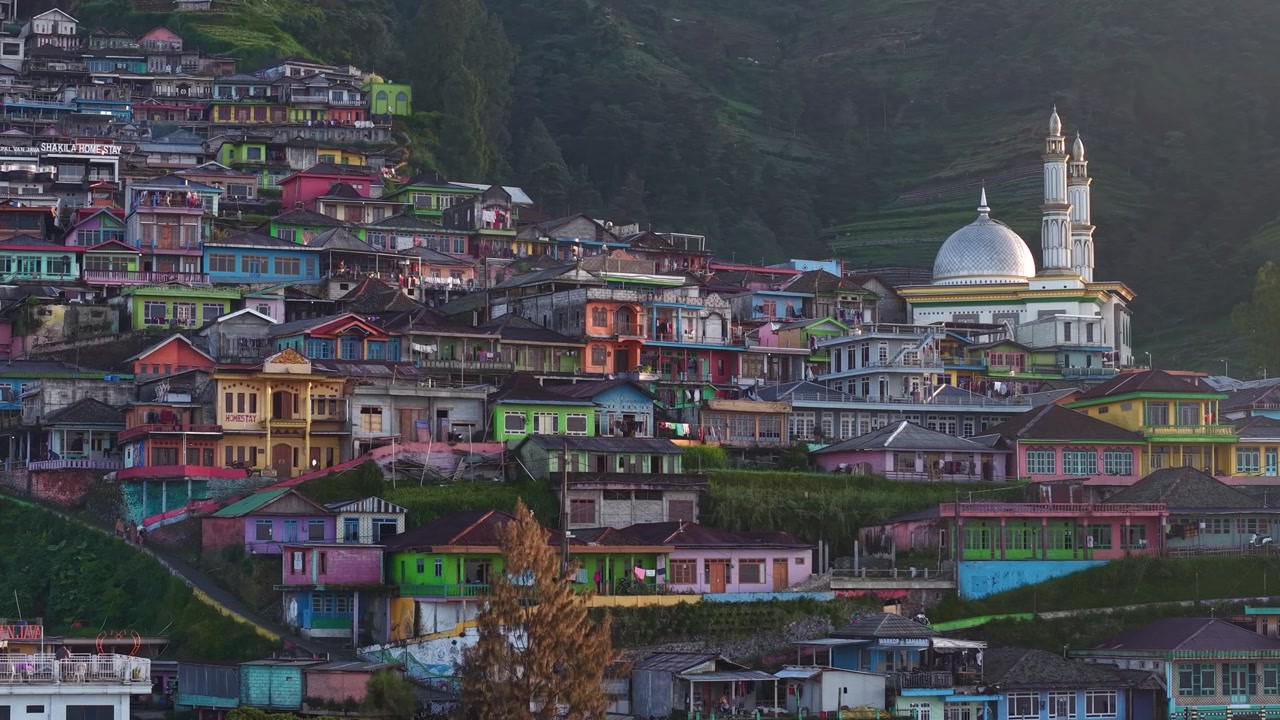 Vista aerea cinematografica di un villaggio di campagna su un fianco di montagna con luce solare drammatica e case colorate. Scenica vita rurale nella natura tropicale di Nepal Van Java, Indonesia.