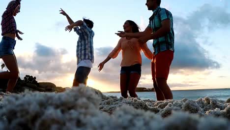 group of friends dancing on the beach