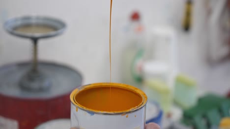 scraping dripping paint from paint pot