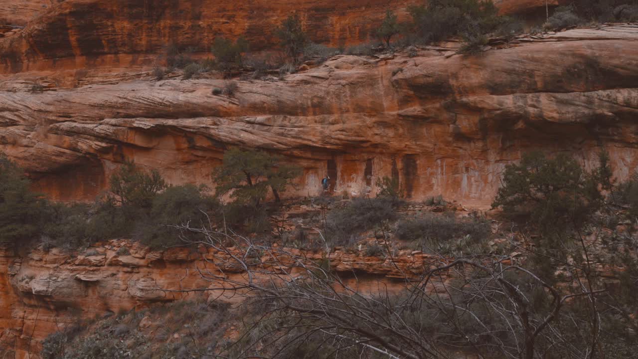 Caucasian male hiker walking across ledge from left to right in Sedona Arizona