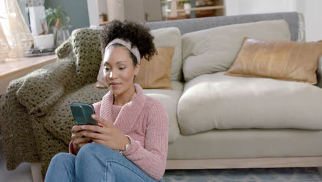 happy biracial woman using smartphone at home, slow motion